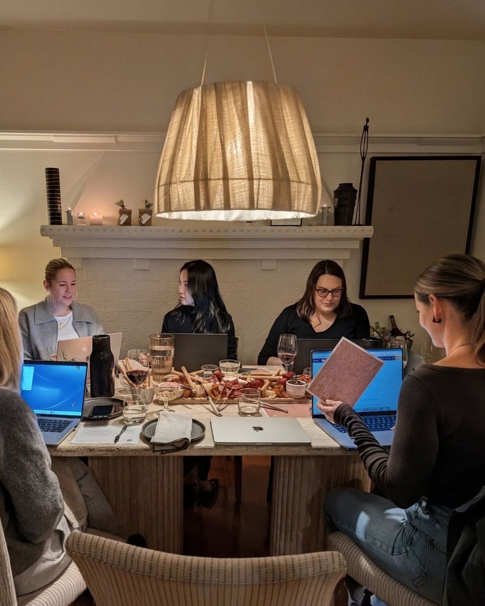 People around a table at night, laptops open